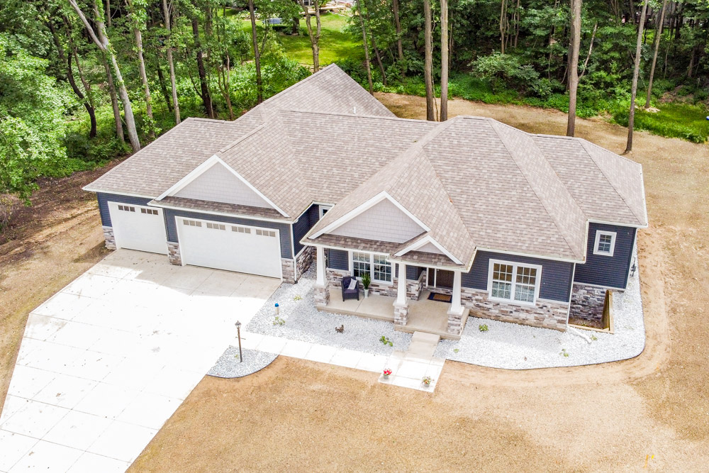 Drone photo of blue ranch home with three car garage